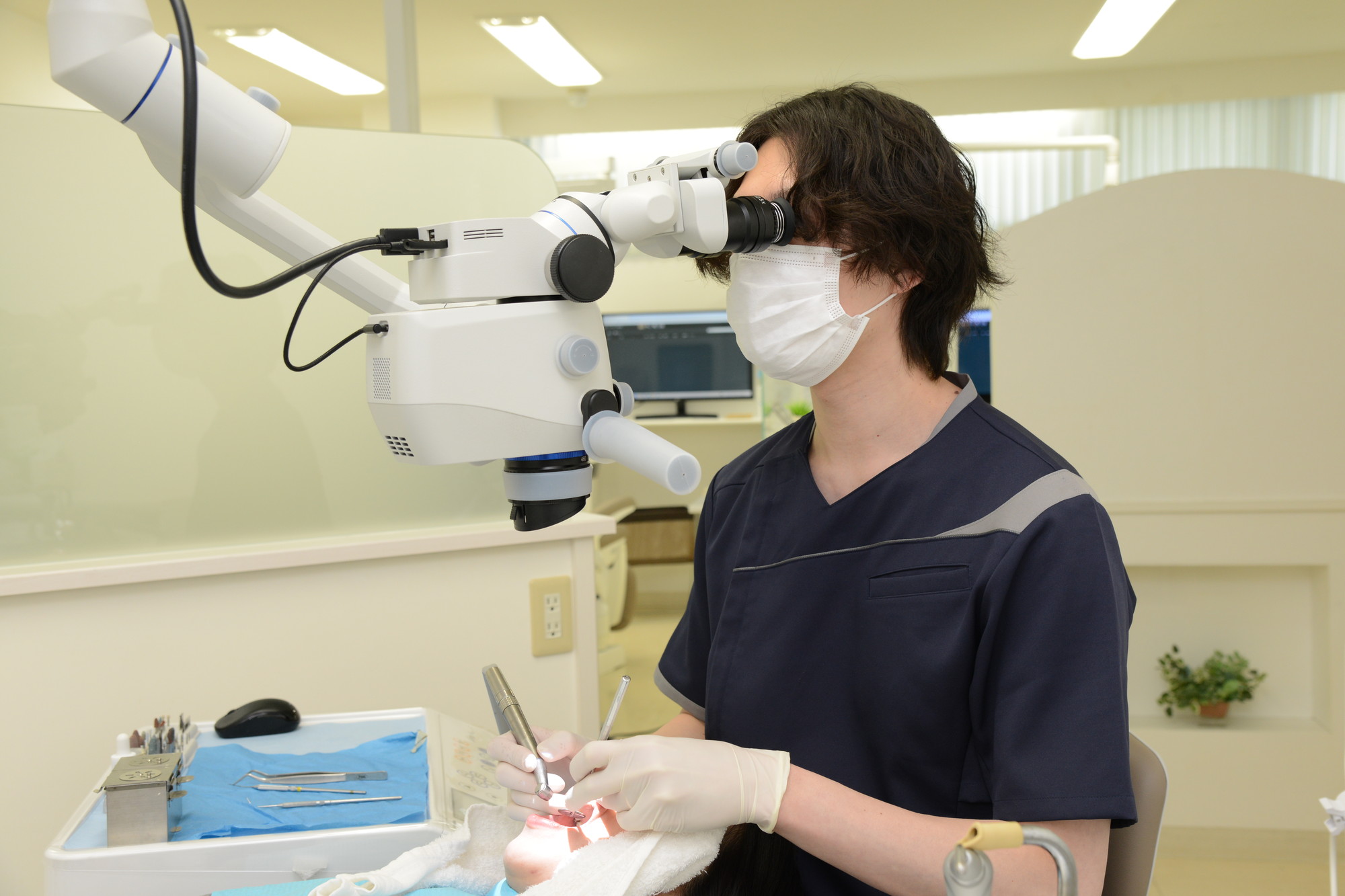 歯科用マイクロスコープを使用して治療する副院長/歯科医師の岡本大典